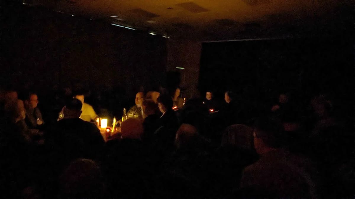 A darkened room during a séance, faces lit only by candlelight