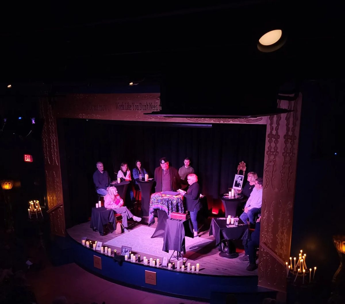 An audience watching a stage séance by Vince Wilson, the stage ringed with candles