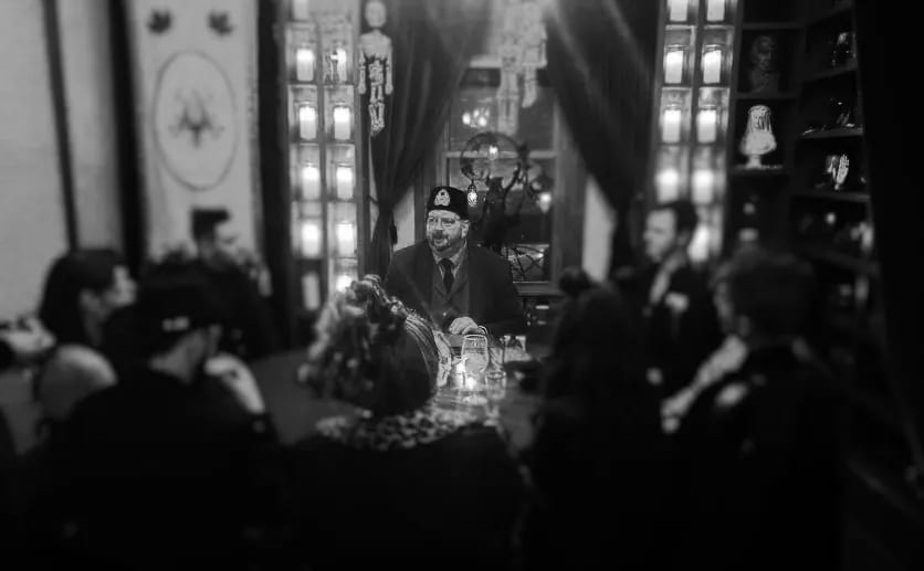 Black and white photo of Vince Wilson leading a candlelit dinner séance